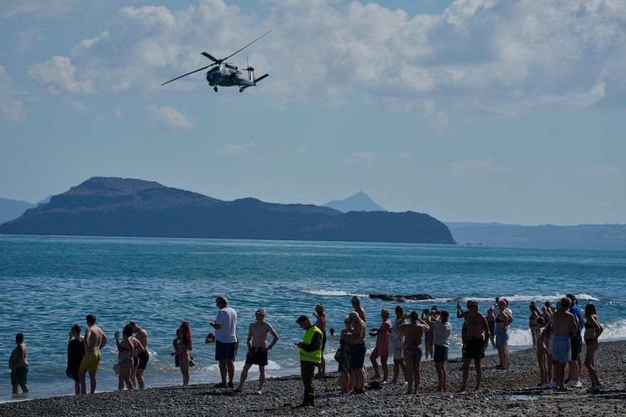 Tourists from nearby hotels watch a military helicopter fly overhead during Medusa 15, a multinational military exercise led by Greece and Egypt, at Maleme on the Greek island of Crete, Friday, Sept. 18, 2026. (AP Photo/Thanassis Stavrakis)