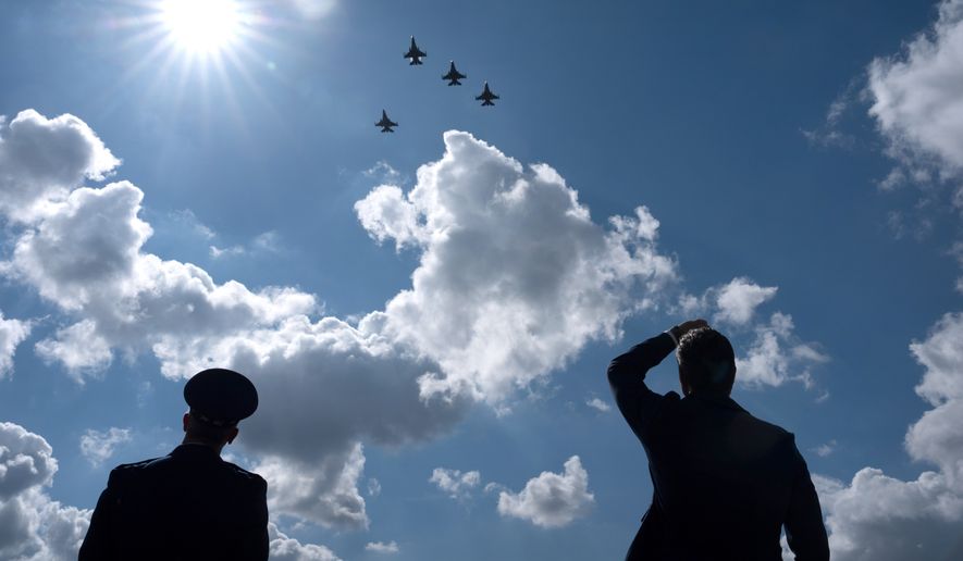 Chairman of the Joint Chiefs of Staff Gen. Dan Caine, left, and Defense Secretary Pete Hegseth, right, stand as Air Force aircraft perform a flyover during the POW/MIA National Recognition Day Ceremony at the Pentagon, Friday, Sept. 18, 2026, in Washington. (AP Photo/Mark Schiefelbein)