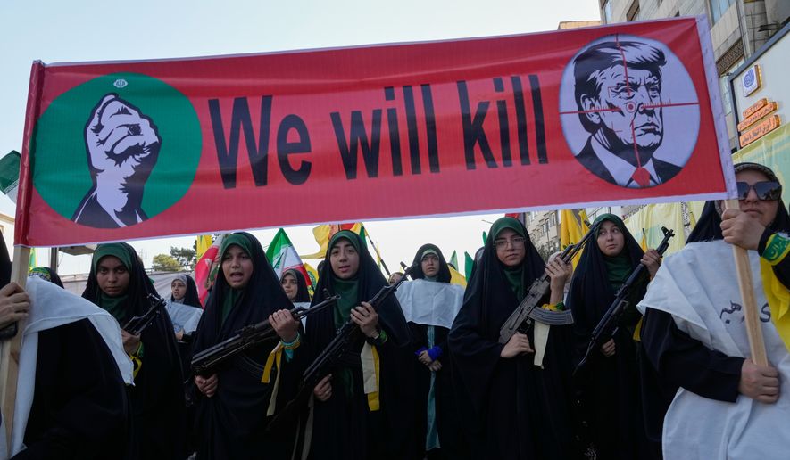 Women affiliated with Iran's Revolutionary Guard carry rifles as they march beneath a banner depicting U.S. President Donald Trump in crosshairs and reading "We will kill" during the state-organized "Janfada," or "Sacrifice for Iran," military-style parade in Tehran, Iran, Friday, Sept. 18, 2026. (AP Photo/Vahid Salemi)