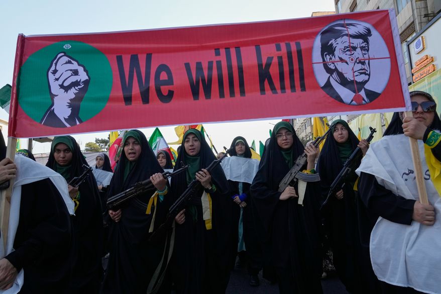 Women affiliated with Iran's Revolutionary Guard carry rifles as they march beneath a banner depicting U.S. President Donald Trump in crosshairs and reading "We will kill" during the state-organized "Janfada," or "Sacrifice for Iran," military-style parade in Tehran, Iran, Friday, Sept. 18, 2026. (AP Photo/Vahid Salemi)