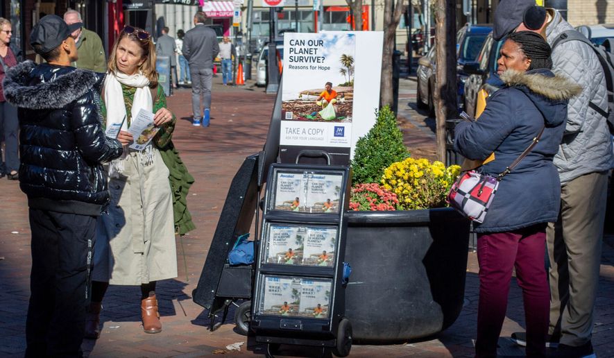 FILE - A woman shares Jehovah's Witnesses' literature with a passerby in downtown Pittsburgh on Nov. 13, 2023. (AP Photo/Peter Smith, File)