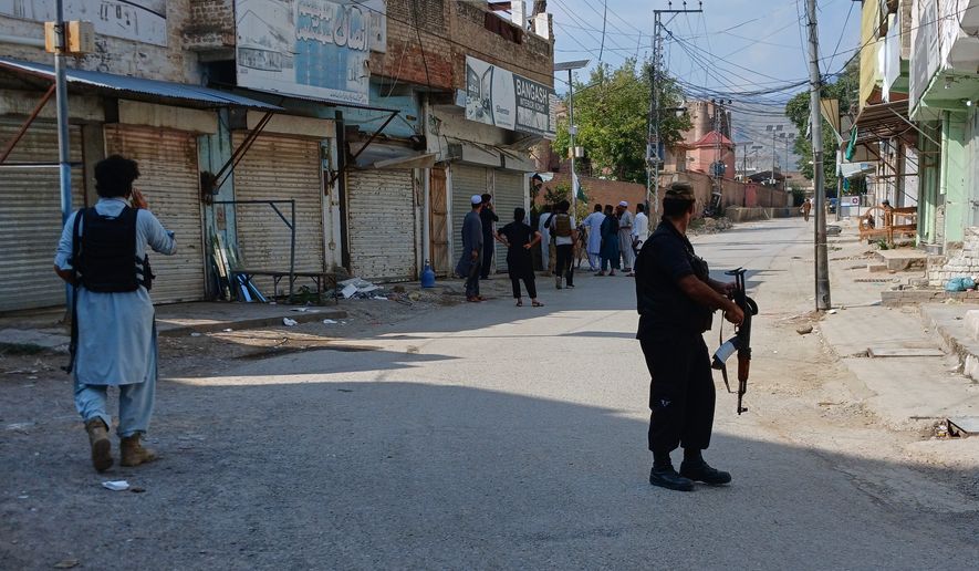 In this photo taken with a smartphone, police officers secure a road leading to the site of a powerful bomb at a mosque in Kohat, Pakistan, Friday, Sept. 18, 2026. (AP Photo/B.S. Gillani)
