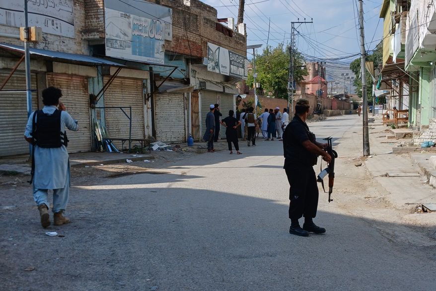 In this photo taken with a smartphone, police officers secure a road leading to the site of a powerful bomb at a mosque in Kohat, Pakistan, Friday, Sept. 18, 2026. (AP Photo/B.S. Gillani)