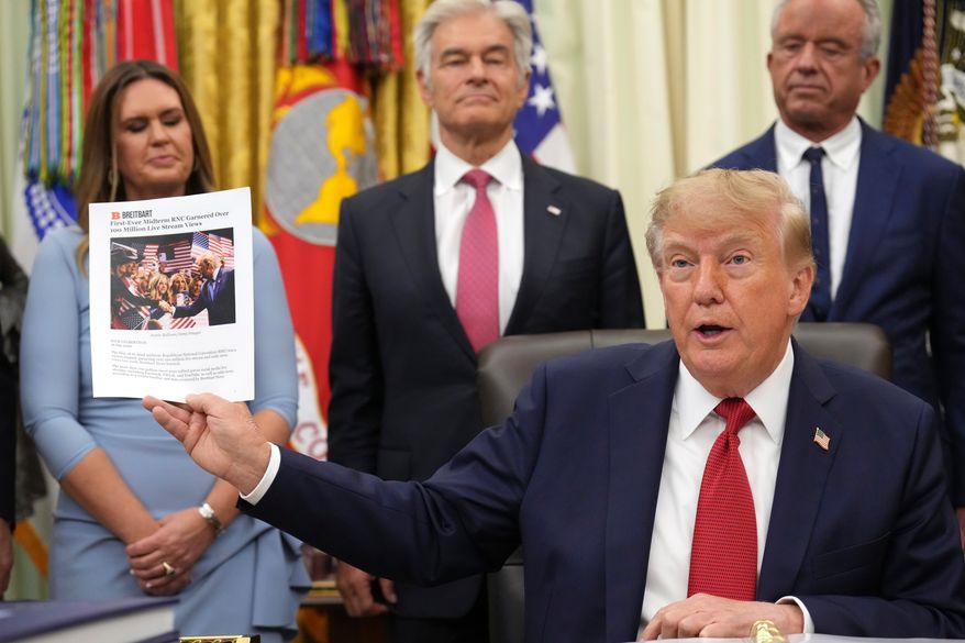 President Donald Trump holds up a printout of a Breitbart article as Arkansas Gov. Sarah Huckabee Sanders, from left, Mehmet Oz, administrator of the Centers for Medicare & Medicaid Services, and Health and Human Services Secretary Robert F. Kennedy Jr., look on during an event about healthcare in the Oval Office of the White House, Friday Sept. 18, 2026, in Washington. (AP Photo/Jacquelyn Martin)