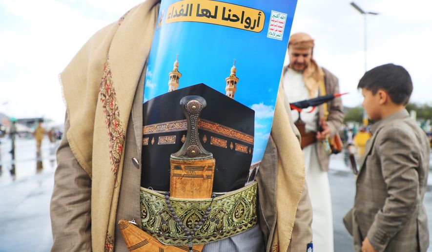 A supporter of Yemen’s Houthi rebels wears a poster showing the Kaaba at the Grand Mosque, tucked into a decorative sash above a dagger, during a rally to protest Saudi Arabia's accusation that the Houthis targeted Islam's holiest site, in Sanaa, Yemen, Friday, Sept. 18, 2026. Arabic reads, "Our souls are sacrificed for it". (AP Photo/Osamah Abdulrahman)