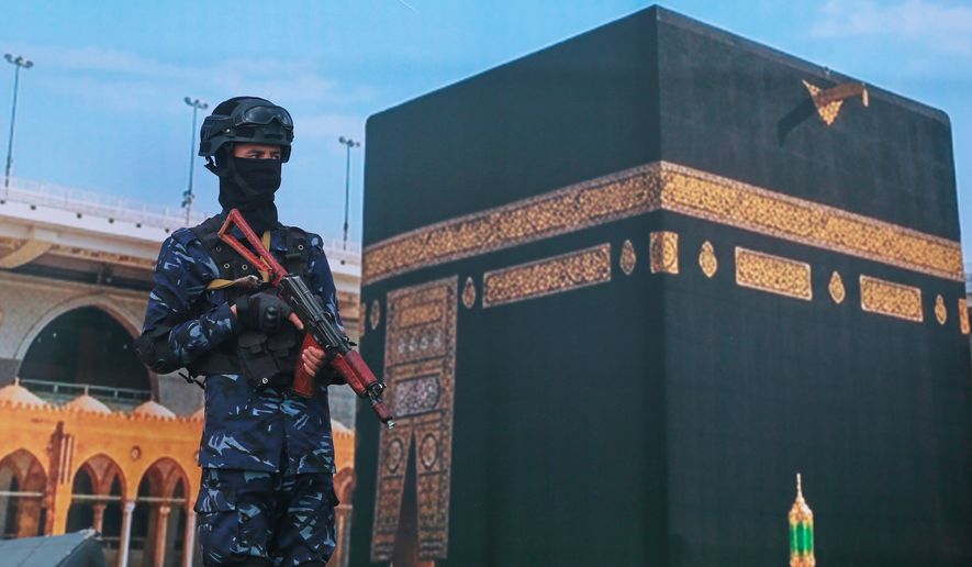 A soldier from Yemen's Houthi rebels stands in front of a giant banner of the Kaaba, during a rally to protest Saudi Arabia's accusation that the Houthis targeted Islam's holiest site in Sanaa, Yemen, Friday, Sept. 18, 2026. (AP Photo/Osamah Abdulrahman)