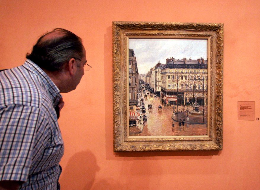 A visitor views the Impressionist painting, "Rue St.-Honore, Apres-Midi, Effet de Pluie," ("Rue Saint-Honoré in the Afternoon, Effect of Rain") painted in 1897 by Camille Pissarro, on display in the Thyssen-Bornemisza Museum in Madrid on May 12, 2005. (AP Photo/Mariana Eliano, File)