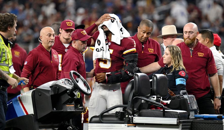 Trainers attend to Washington Commanders quarterback Jayden Daniels (5) after an apparent injury in the first half against the Dallas Cowboys during an NFL football game in Arlington, Texas, Sunday, Sept. 20, 2026. (AP Photo/Jessica Tobias)
