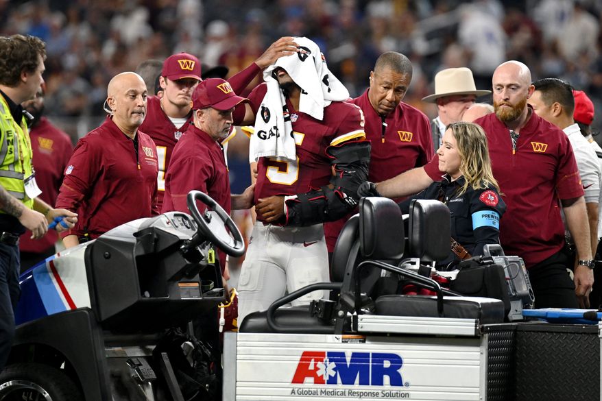 Trainers attend to Washington Commanders quarterback Jayden Daniels (5) after an apparent injury in the first half against the Dallas Cowboys during an NFL football game in Arlington, Texas, Sunday, Sept. 20, 2026. (AP Photo/Jessica Tobias)