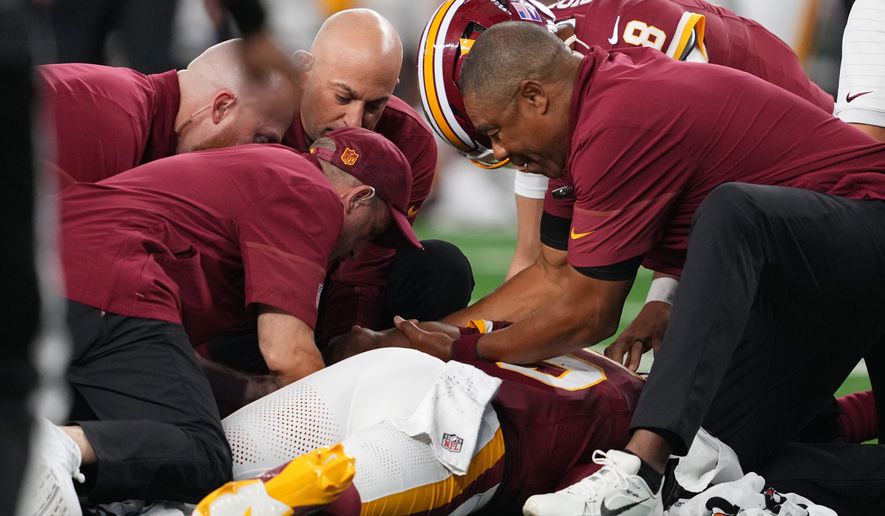 Trainers attend to Washington Commanders quarterback Jayden Daniels (5) after an apparent injury in the first half against the Dallas Cowboys during an NFL football game in Arlington, Texas, Sunday, Sept. 20, 2026. (AP Photo/Tony Gutierrez)