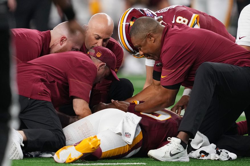 Trainers attend to Washington Commanders quarterback Jayden Daniels (5) after an apparent injury in the first half against the Dallas Cowboys during an NFL football game in Arlington, Texas, Sunday, Sept. 20, 2026. (AP Photo/Tony Gutierrez)