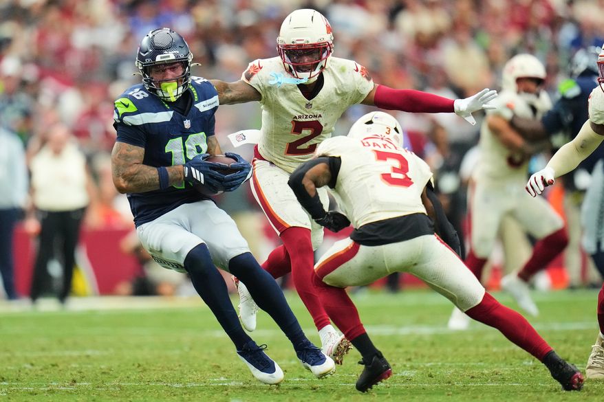 Seattle Seahawks tight end Elijah Arroyo (18) makes a catch against Arizona Cardinals cornerback Will Johnson (2) and safety Budda Baker (3) during the second half of an NFL football game in Glendale, Ariz., Sunday, Sept. 20, 2026. (AP Photo/Rick Scuteri)