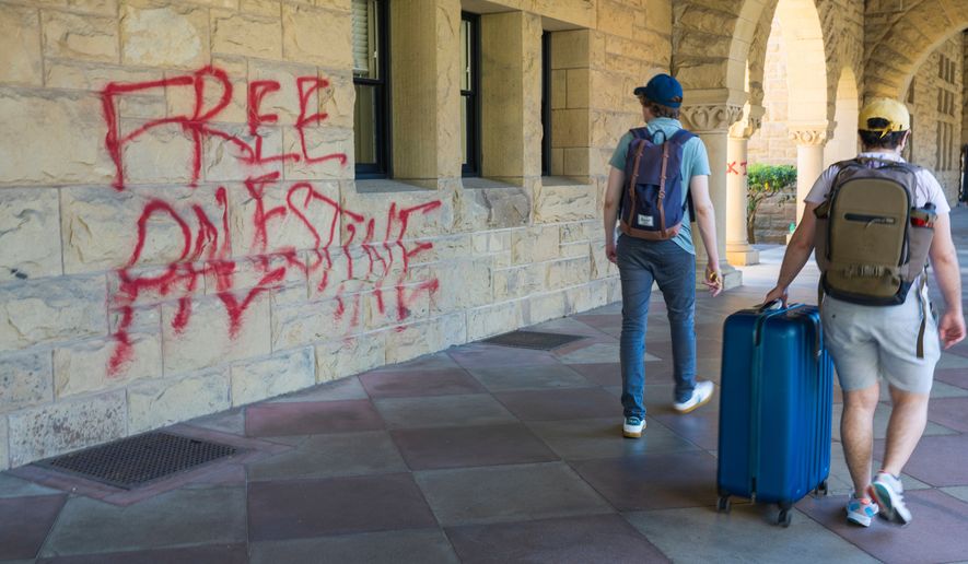 FILE - Students walk by graffiti near President Richard Saller's office at Stanford University in Palo Alto, Calif., June 5, 2024. (AP Photo/Nic Coury, File)