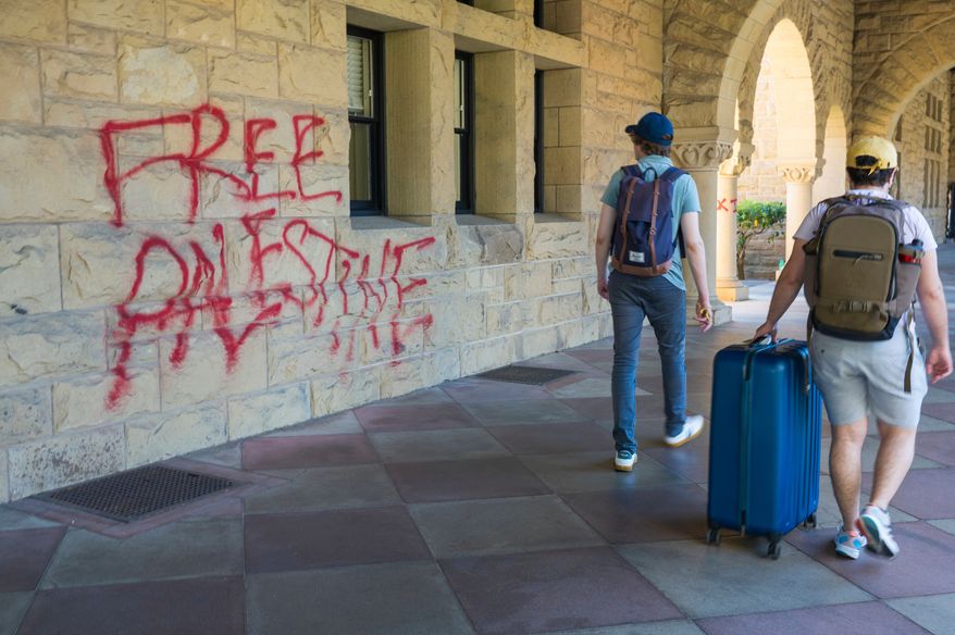 FILE - Students walk by graffiti near President Richard Saller's office at Stanford University in Palo Alto, Calif., June 5, 2024. (AP Photo/Nic Coury, File)