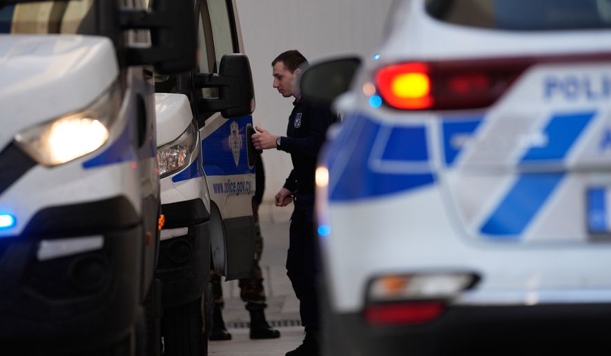 Police officers stand by police vehicles at the courthouse complex in the southwest coastal city of Paphos, Cyprus, Tuesday, Dec. 13, 2022. (AP Photo/Petros Karadjias)