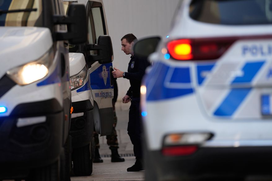 Police officers stand by police vehicles at the courthouse complex in the southwest coastal city of Paphos, Cyprus, Tuesday, Dec. 13, 2022. (AP Photo/Petros Karadjias)