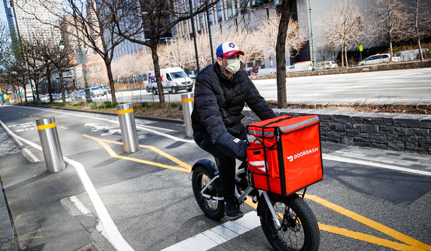 FILE - A delivery worker rides his bicycle along a path on the West Side Highway in New York on March 16, 2020. (AP Photo/John Minchillo, File)