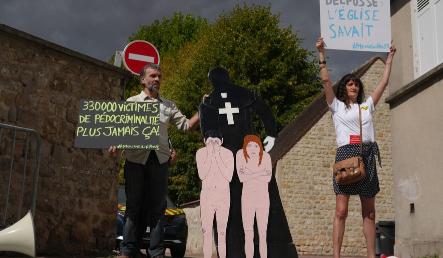 Activists fighting child abuse stage a protest near the home of a former Catholic priest suspected of sexually assaulting dozens of children, in Etrechy, outside Paris, Wednesday, Sept 16, 2026, Placards read from the left: '330,000 victims of child sexual abuse, never again' and Delfosse, the church knew'. (AP Photo/Thibault Camus)