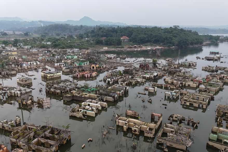 Long-submerged houses are exposed after prolonged drought lowers the water level of Karian Dam, in Lebak, Banten Province, Indonesia, Friday, July 31, 2026. (AP Photo/Tatan Syuflana)