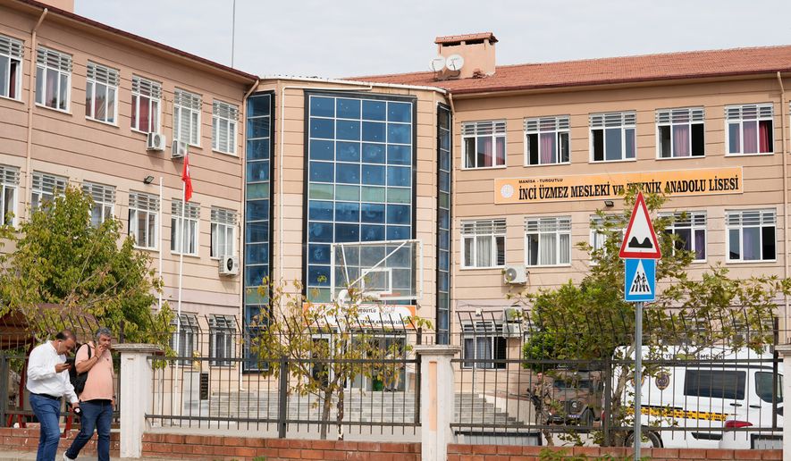 People walk past a vocational and technical high school in the Turgutlu district of Manisa province, western Turkey, Tuesday, Sept. 22, 2026, after a gunman opened fire near the school. (IHA via AP)