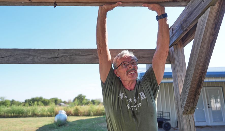 Ed Westrick, 59, adjusts a roof on a small building at his rural home near Commerce, Texas, Friday, Sept. 18, 2026. (AP Photo/LM Otero)