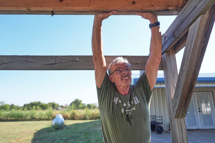 Ed Westrick, 59, adjusts a roof on a small building at his rural home near Commerce, Texas, Friday, Sept. 18, 2026. (AP Photo/LM Otero)