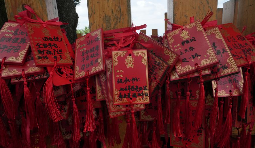 Red cards written with wishes are tied to a fence near the Golden Hall in Wudang Mountains in central China's Hubei Province on Sept. 3, 2026. (AP Photo/Achmad Ibrahim)
