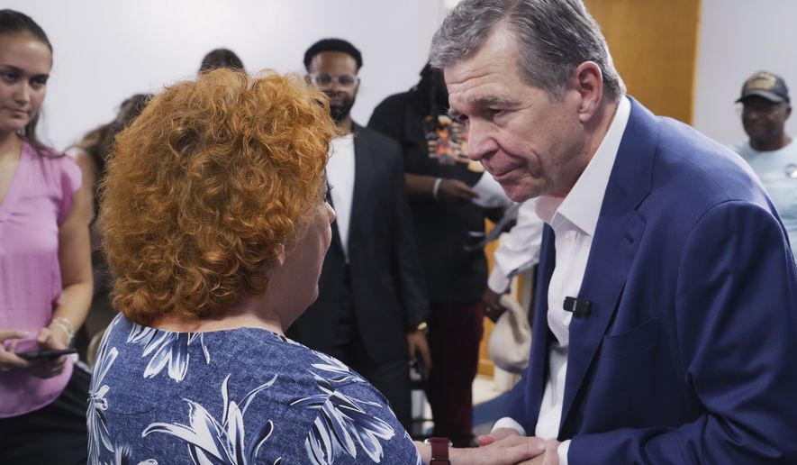 Former Democratic Gov. Roy Cooper, who is running for U.S. Senate, holds hands with a woman following a campaign event at St. James African Methodist Episcopal Church in Goldsboro, N.C., on Thursday, Sept. 10, 2026. (AP Photo/Allen G. Breed)