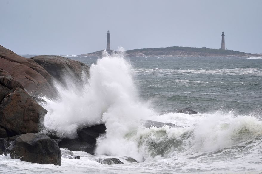 Surf breaks along the rocky coastline, with the twin lighthouses of Thatcher Island visible in the distance, during the early stages of a nor’easter Friday, Sept. 25, 2026, in Gloucester, Mass. (AP Photo/Robert F. Bukaty)