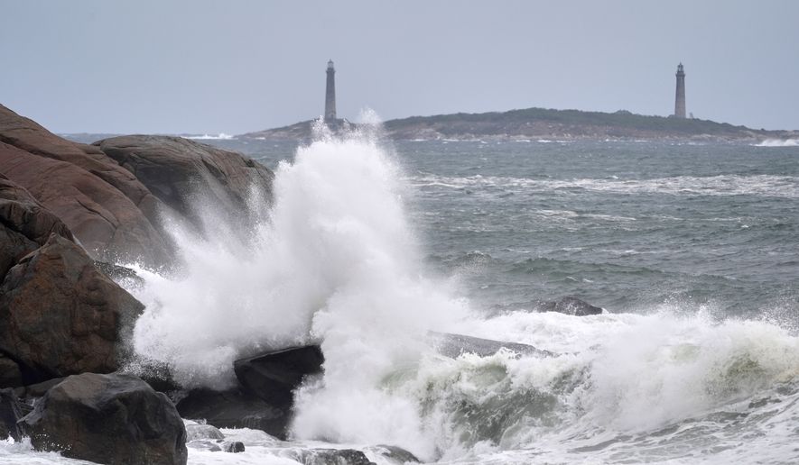Surf breaks along the rocky coastline, with the twin lighthouses of Thatcher Island visible in the distance, during the early stages of a nor’easter Friday, Sept. 25, 2026, in Gloucester, Mass. (AP Photo/Robert F. Bukaty)