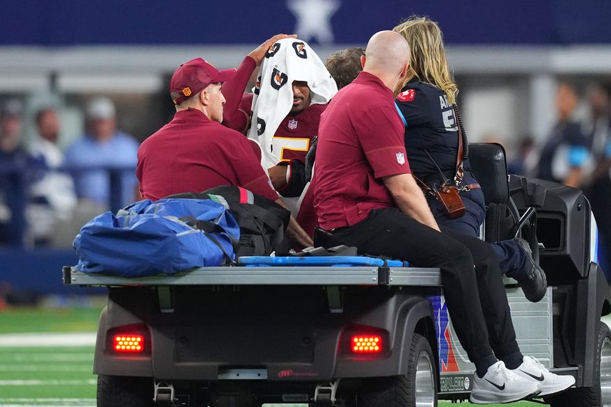 Washington Commanders quarterback Jayden Daniels (5) is carted off the field after an apparent injury in the first half against the Dallas Cowboys during an NFL football game in Arlington, Texas, Sunday, Sept. 20, 2026. (AP Photo/Julio Cortez)