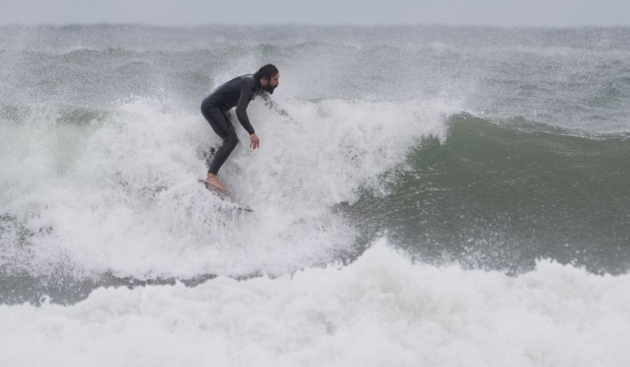A surfer rides a wave during a nor'easter storm, Friday, Sept. 25, 2026, in Gloucester, Mass.(AP Photo/Robert F. Bukaty)