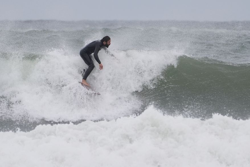 A surfer rides a wave during a nor'easter storm, Friday, Sept. 25, 2026, in Gloucester, Mass.(AP Photo/Robert F. Bukaty)