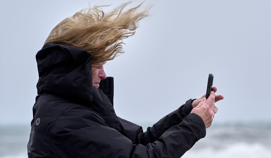 Denise Taylor of Manchester, N.H., is buffeted by the wind as she films the raging sea during a nor'easter storm in Hampton, N.H., Saturday, Sept. 26, 2026. (AP Photo/Robert F. Bukaty)