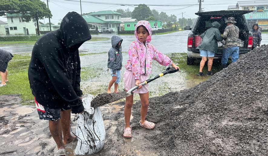 Kenzielynn Kekoa, center, of Hilo, Hawaii, helps her family fill sand bags as Hurricane Nolo approaches in Hilo, Hawaii, Friday, Sept. 25, 2026. (AP Photo/Eugene Garcia)