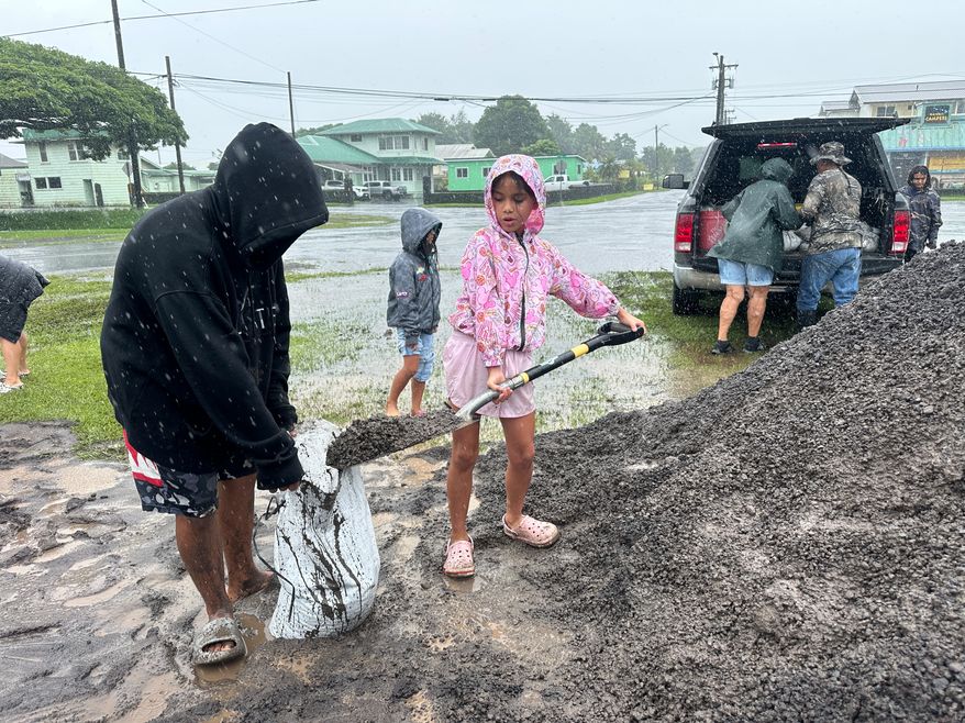 Kenzielynn Kekoa, center, of Hilo, Hawaii, helps her family fill sand bags as Hurricane Nolo approaches in Hilo, Hawaii, Friday, Sept. 25, 2026. (AP Photo/Eugene Garcia)