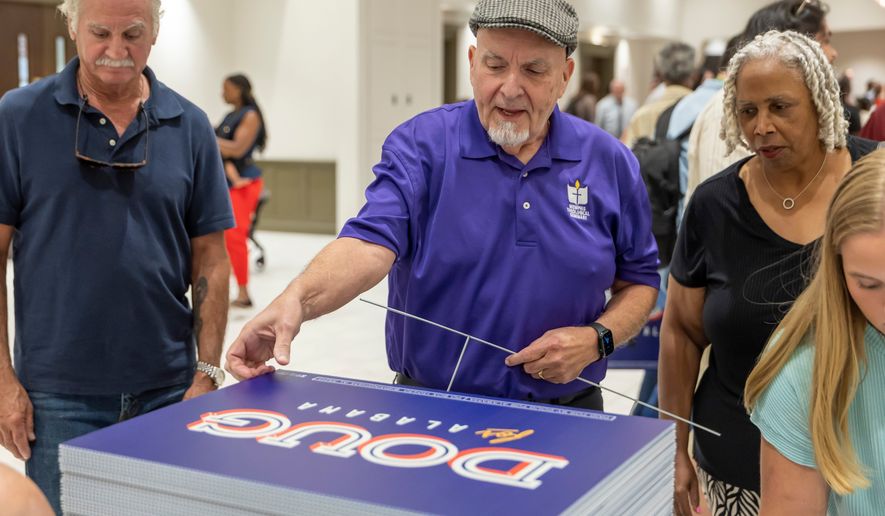 Michael Davis, of Bellwood, Ala., picks up a sign supporting Doug Jones for governor after a town hall hosted by Troy University College Democrats and the Pike County Democrats, Aug. 18, 2026, in Troy, Ala. (AP Photo/Vasha Hunt, File)