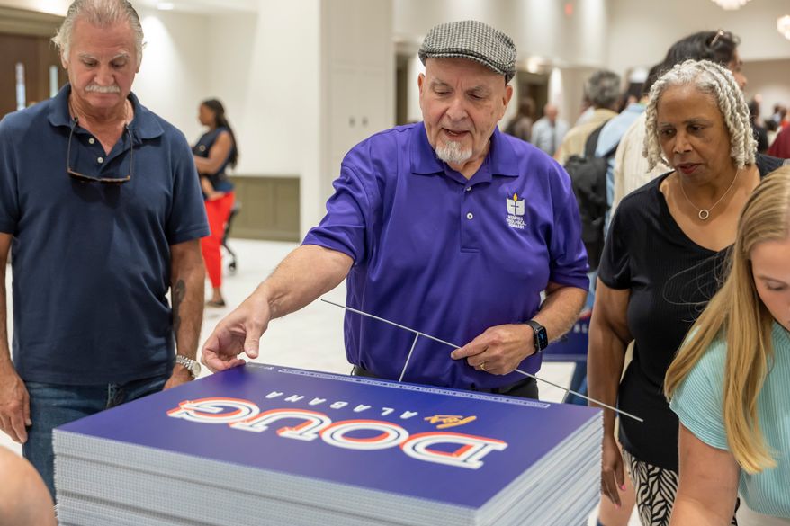 Michael Davis, of Bellwood, Ala., picks up a sign supporting Doug Jones for governor after a town hall hosted by Troy University College Democrats and the Pike County Democrats, Aug. 18, 2026, in Troy, Ala. (AP Photo/Vasha Hunt, File)