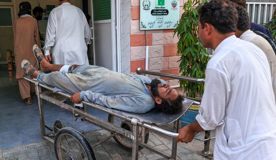 In this photo taken with a smartphone, volunteers transport an injured victim of a suicide attack on a roadside police checkpoint upon his arrival at a hospital in Dera Ismail Khan, Pakistan, Saturday, Sept. 26, 2026. (AP Photo/Kashif Naveed)