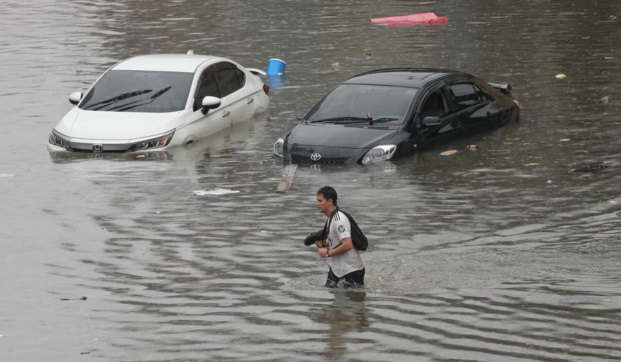 Man wades through floodwaters after heavy rain in Bangkok, Thailand, Saturday, Sept. 26, 2026. (AP Photo/Sakchai Lalit)
