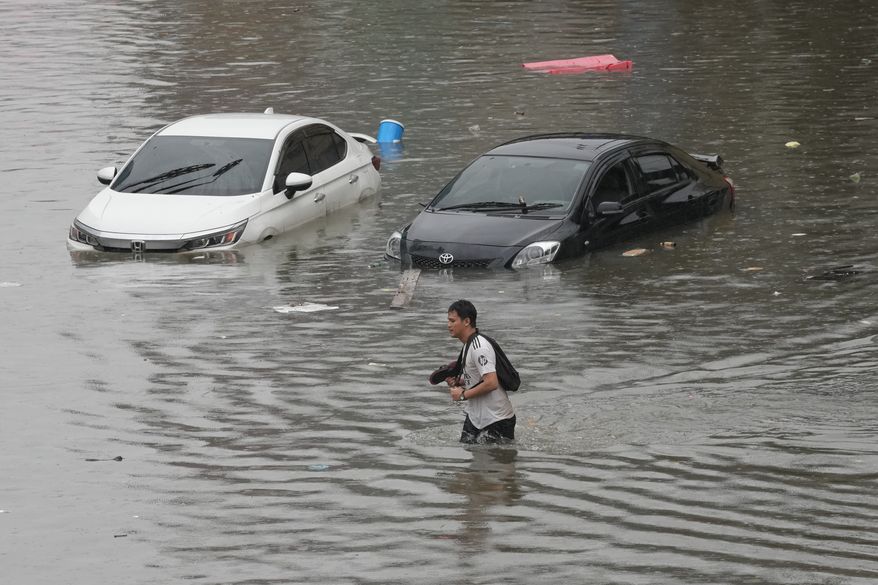 Man wades through floodwaters after heavy rain in Bangkok, Thailand, Saturday, Sept. 26, 2026. (AP Photo/Sakchai Lalit)