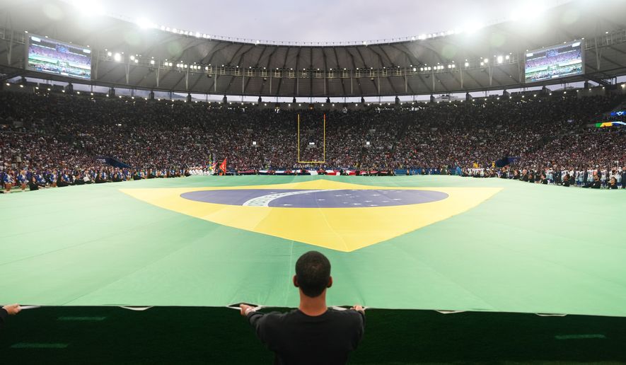 Crews hold a Brazilian flag on the field before an NFL football game between the Dallas Cowboys and the Baltimore Ravens in Rio de Janeiro, Sunday, Sept. 27, 2026. (AP Photo/Fernando Llano)