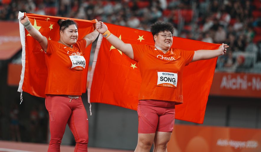 China's Song Jiayuan, right, and Zhang Linru hold their flags after competing in the women's shot put final at the Asian Games in Nagoya, Japan, Friday, Sept. 25, 2026. (AP Photo/Lee Jin-man)