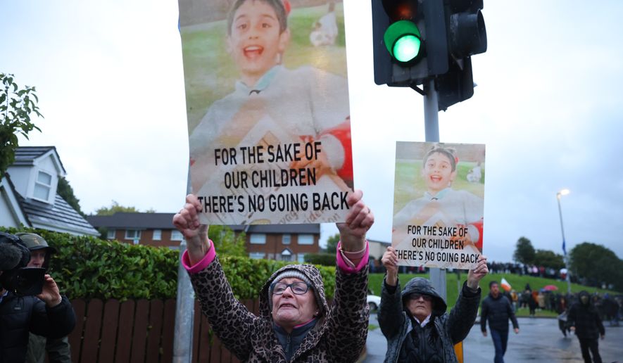 Protesters hold banners ahead of a Portadown District Loyal Orange Lodge (LOL) No 1 march in the first parade for almost 30 years, after the parade was given clearance in a late-night hearing, in Portadown, Northern Ireland, Sunday, Sept. 27, 2026. (Peter Morrison/PA via AP)