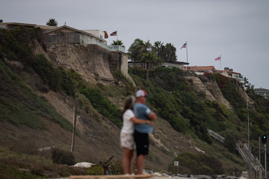 A couple hug at North Beach as crumbling seaside bluffs are seen behind them in San Clemente, Calif., Friday, Sept. 18, 2026. (AP Photo/Jae C. Hong)