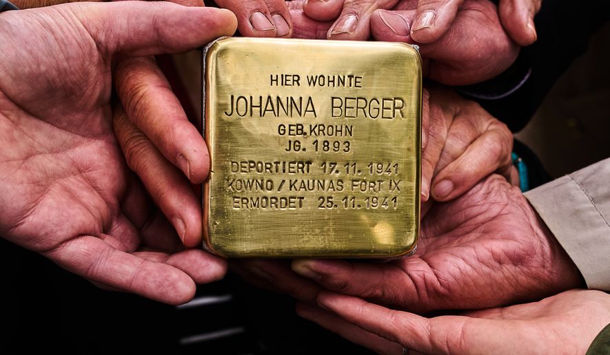 Relatives pose for a photograph holding a palm-sized brass Holocaust plaque in German reading, "Johanna Berger, born in 1893, lived here; deported on Nov. 17, 1941, murdered on Nov. 25, 1941 in Kowno/Kaunas Fort IX," by artist Gunter Demnig prior to the placing of the so called, "Stolperstein," or "Stumbling Blocks," in front of her former home in Berlin, Germany, May 6, 2026. (AP Photo/Markus Schreiber, File)
