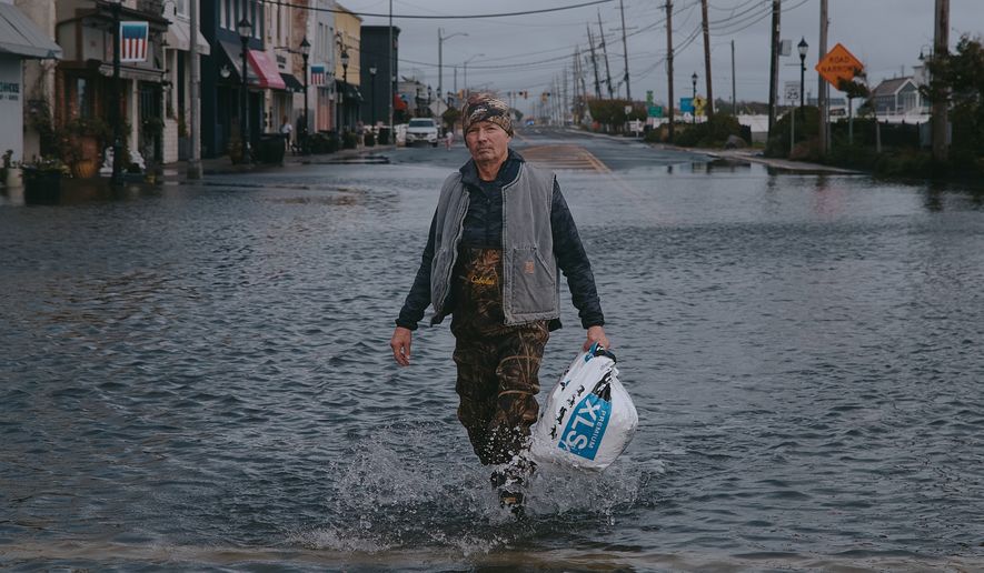 Bernard Dowd walks along a flooded street during a nor'easter storm on Sunday, Sept. 27, 2026, in Sea Bright, N.J. (AP Photo/Andres Kudacki)