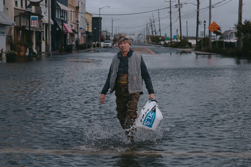 Bernard Dowd walks along a flooded street during a nor'easter storm on Sunday, Sept. 27, 2026, in Sea Bright, N.J. (AP Photo/Andres Kudacki)