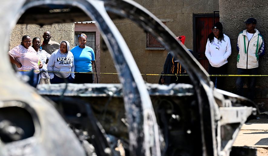 Community members stand at scene of a mass shooting on Saturday night when suspects opened fire at a bar in Wedela township, southwest of Johannesburg, South Africa, Sunday, Sept. 27, 2026. (AP Photo)