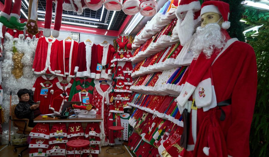 A vendor waits for customers near Santa costumes for sale at the Yiwu International Trade Market in Yiwu, eastern China's Zhejiang province on April 10, 2025. (AP Photo/Ng Han Guan, File)